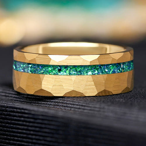 Gold tungsten ring with green emerald inlay on a hammered surface