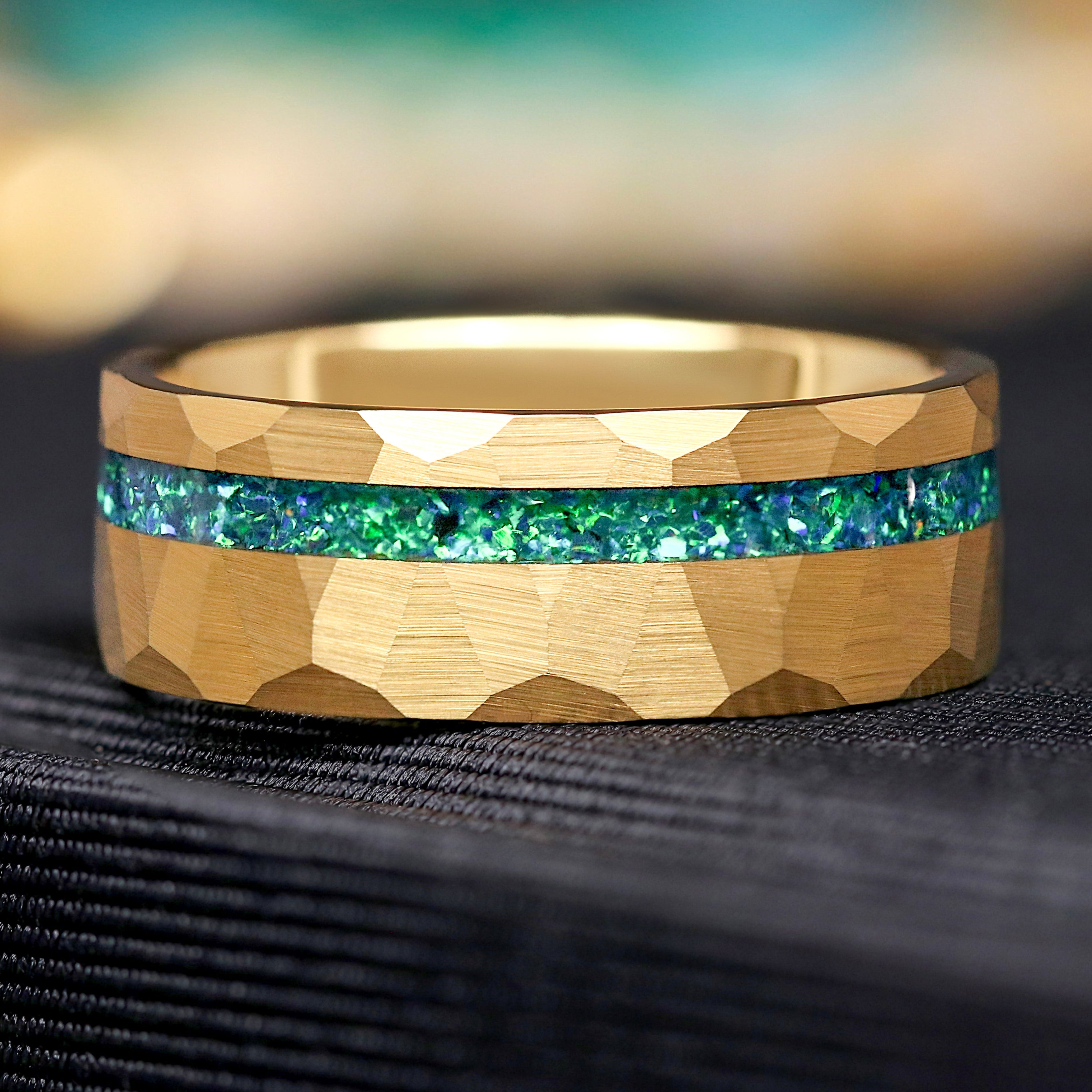 Gold tungsten ring with green emerald inlay on a hammered surface