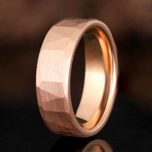 Men's 7mm hammered rose gold tungsten wedding band standing at an angle, close crop