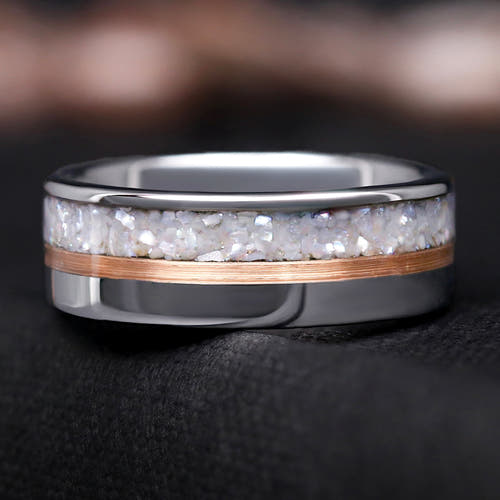 Silver ring with a rose gold accent and white pearl inlay on a dark background