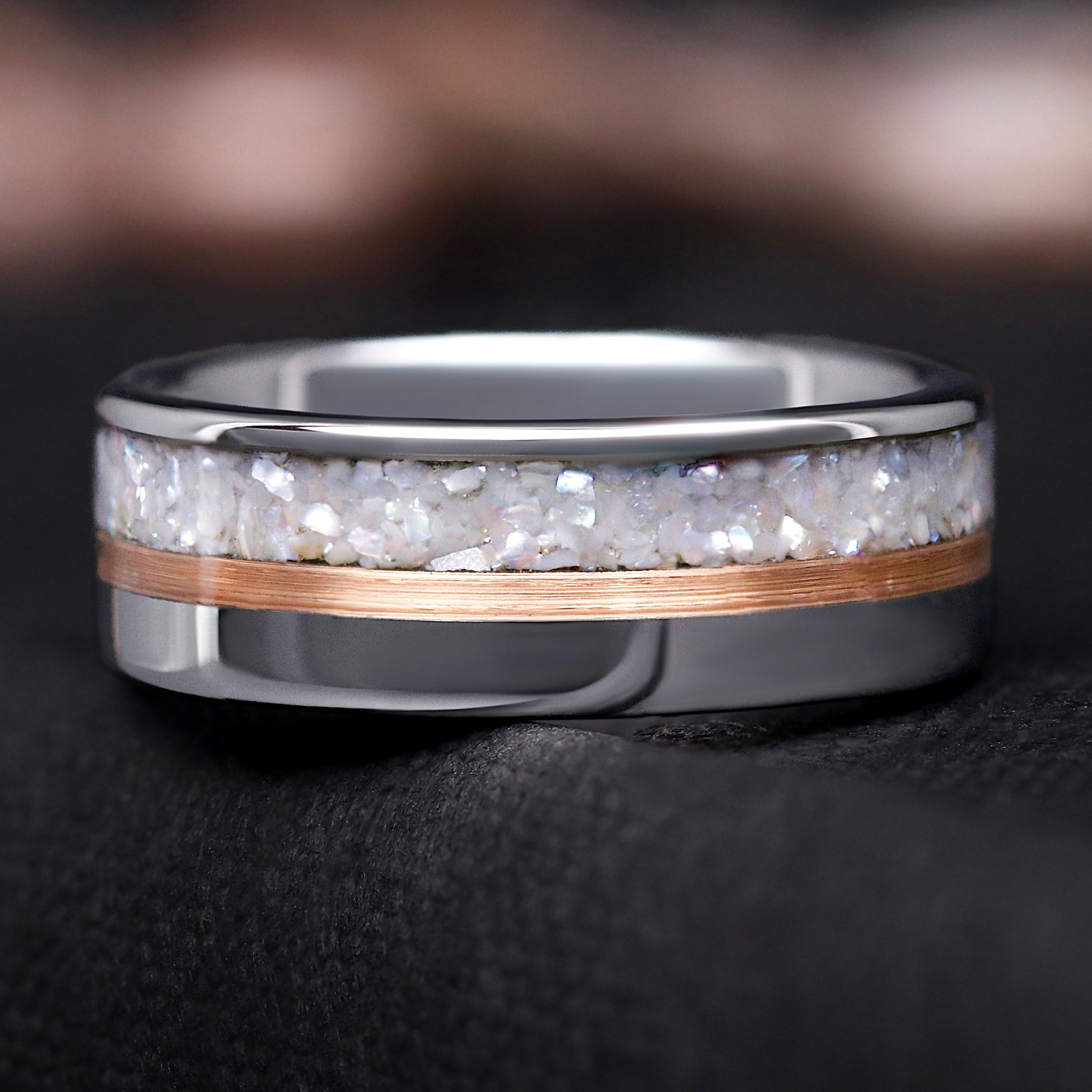 Silver ring with a rose gold accent and white pearl inlay on a dark background