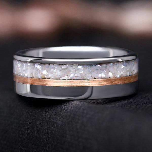Silver ring with a rose gold accent and white pearl inlay on a dark background
