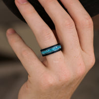 Men's black tungsten band with aquamarine inlay worn on a hand