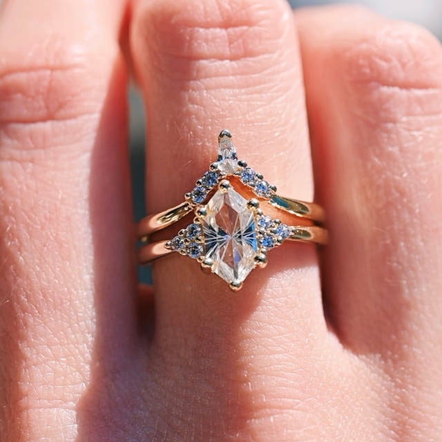 Gold elongated hexagon engagement ring and curved band worn on a woman's hand