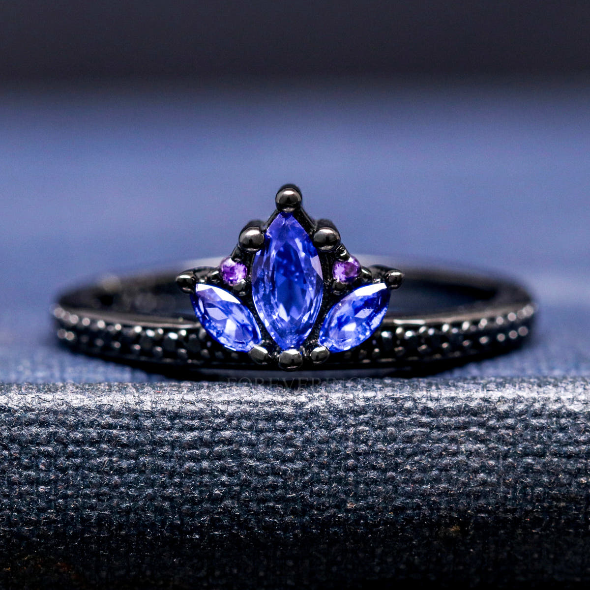 Women's black sterling silver lotus ring with blue sapphire petals and amethyst accents