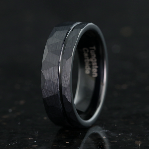 Men's 7mm matte black hammered tungsten wedding band with an offset groove, standing upright
