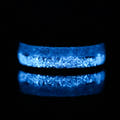 Tungsten ring photographed in the dark, its inlay glowing bright blue
