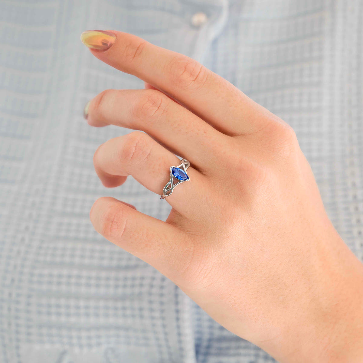 Women's sterling silver ring with a marquise blue sapphire, worn on a hand