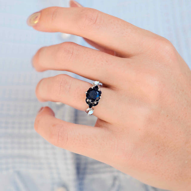 Blue sandstone ring with white opal accents in sterling silver, worn on a woman's hand