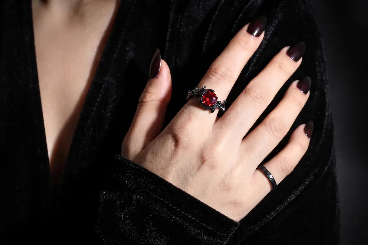 Black engagement ring with red stone and hammered black band on hand