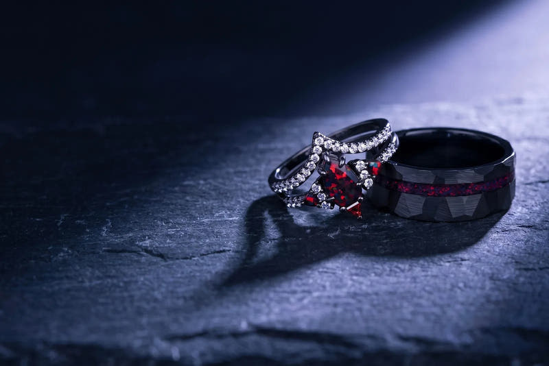 Black fire opal gothic couples ring set: her black opal ring beside his hammered band with red opal inlay