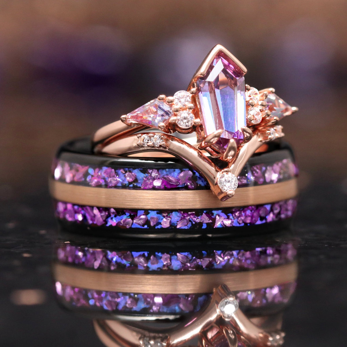 Matching couples ring set, rose gold alexandrite bridal set resting on a black and rose gold tungsten band