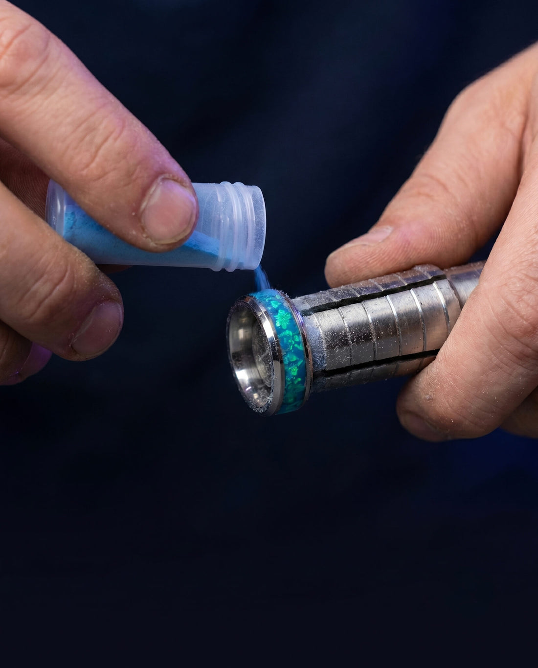 A Foreverings jeweler hand-setting crushed blue opal into a tungsten ring in the Florida workshop