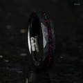 Women's 4mm black hammered tungsten ring with black fire opal inlay, standing on edge