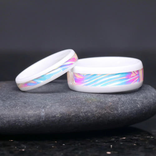 Matching white ceramic couples ring set with dichrolam inlay, 8mm and 4mm, her ring leaning on his