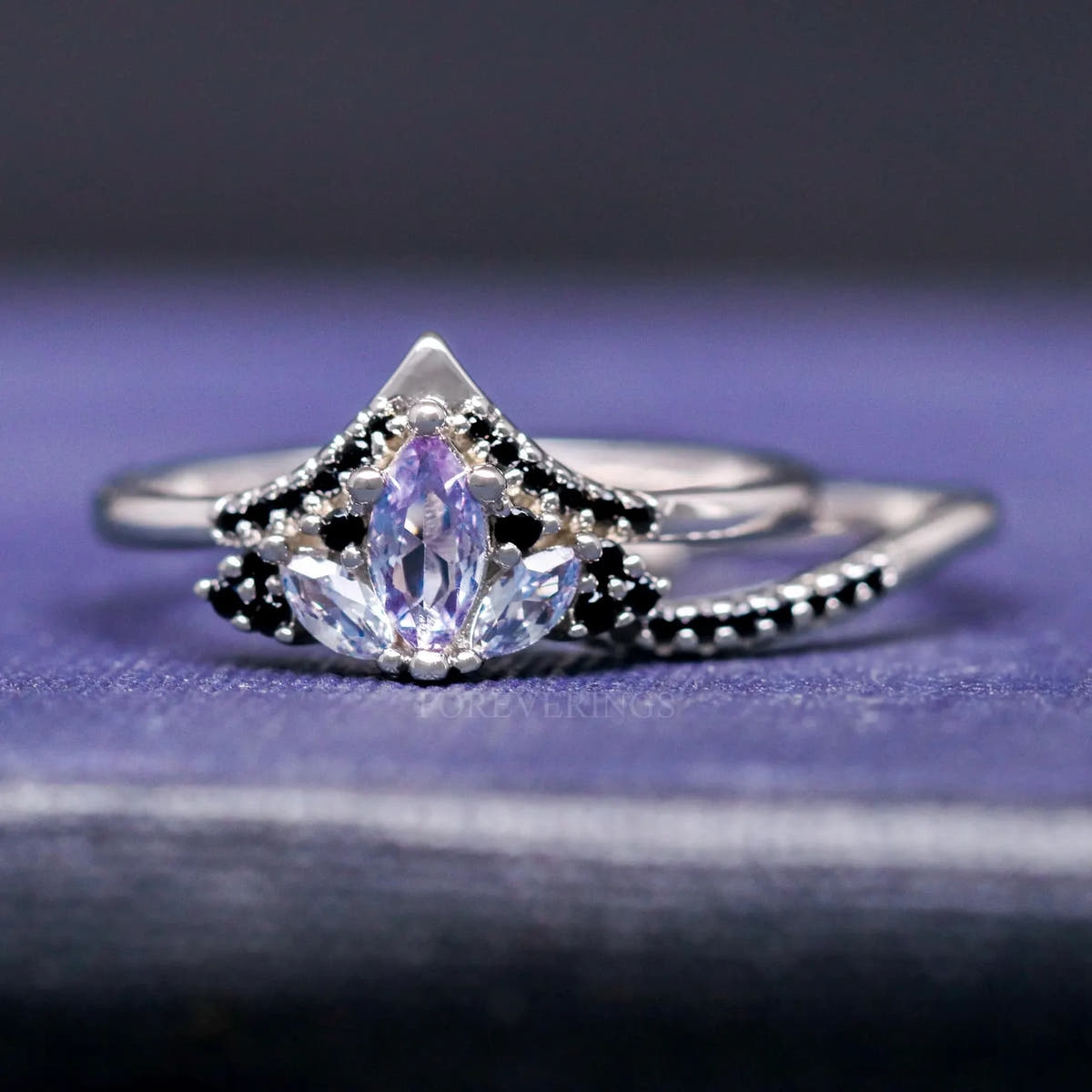 Angled view of the silver alexandrite ring nested in a curved band lined with black accent stones