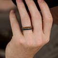 Rose gold tungsten band with whiskey barrel wood and coffee inlay worn on a man's hand