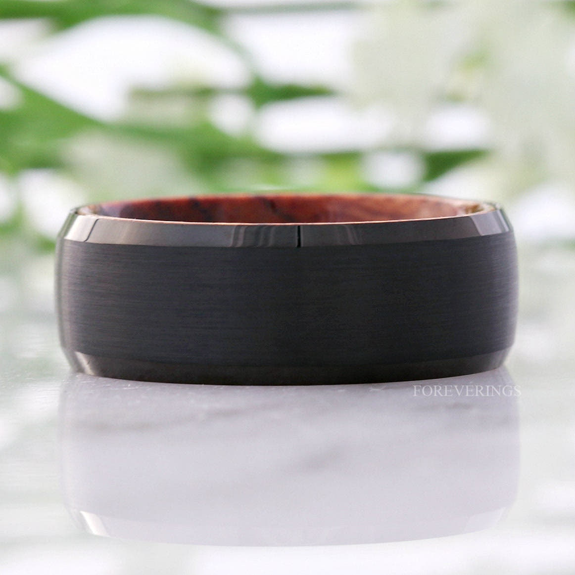 Black tungsten wood-lined band lying flat, front view with the rosewood edge showing