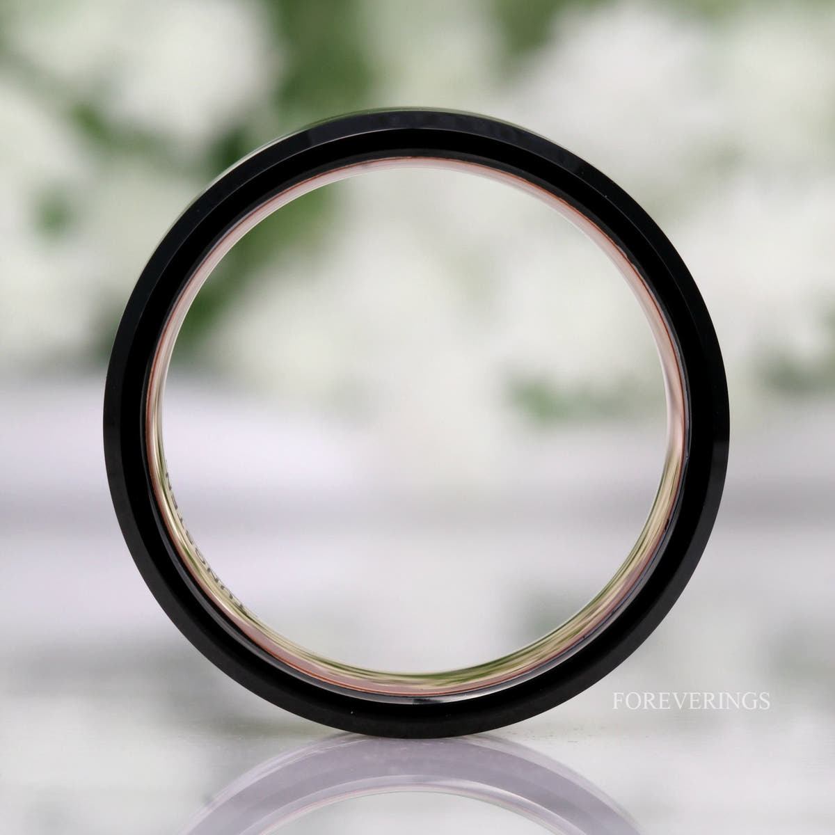 Black tungsten ring seen straight on through the center, rose gold lining visible