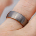 Men's 8mm matte silver tungsten band worn on a finger, rose gold edge showing