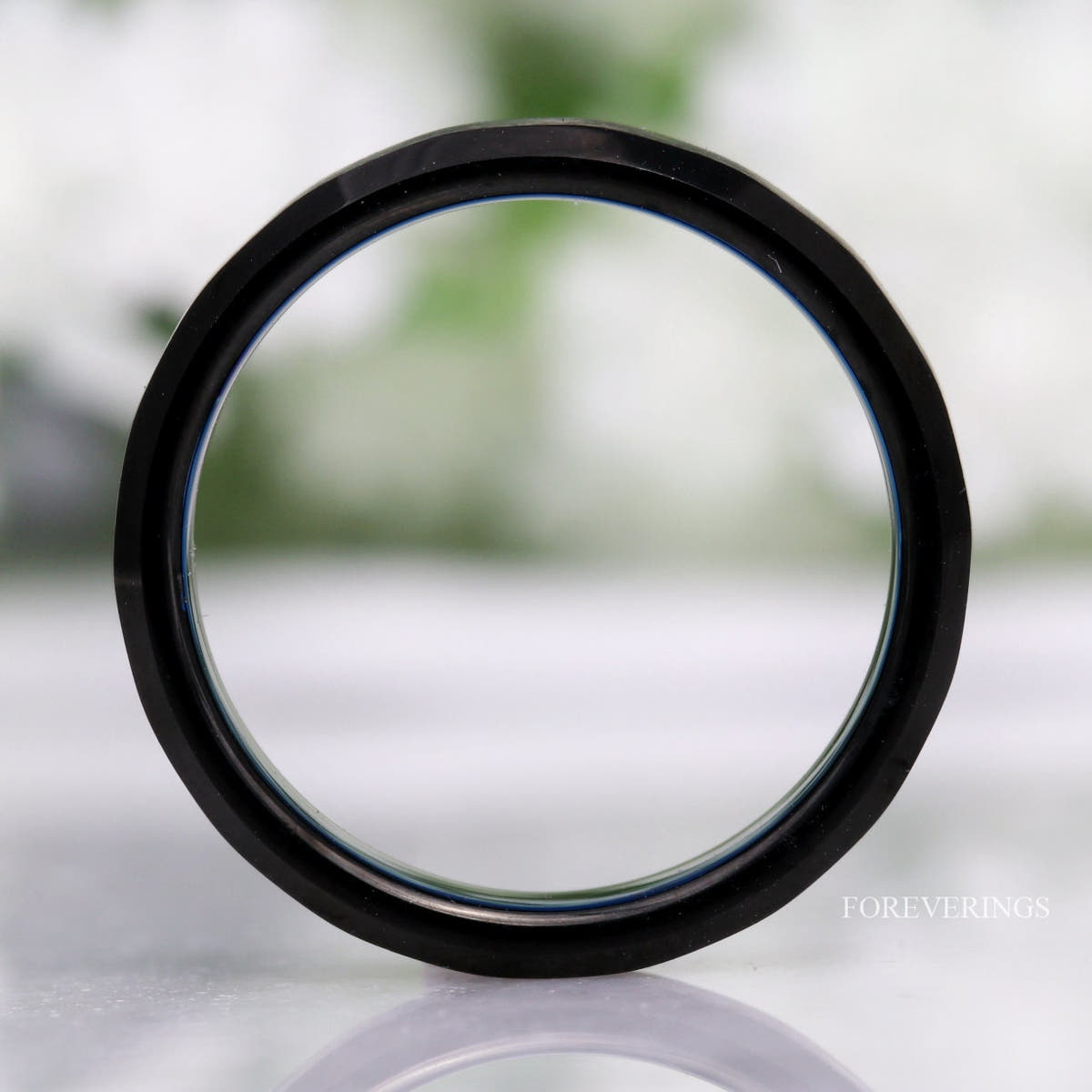 Black and blue tungsten ring standing upright, viewed straight through the band