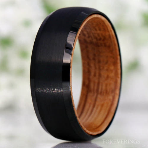 Men's brushed black tungsten band with whiskey barrel wood lining, standing close-up