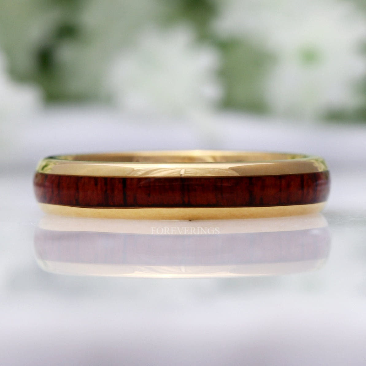Gold tungsten band with koa wood inlay shown straight on, reflection below