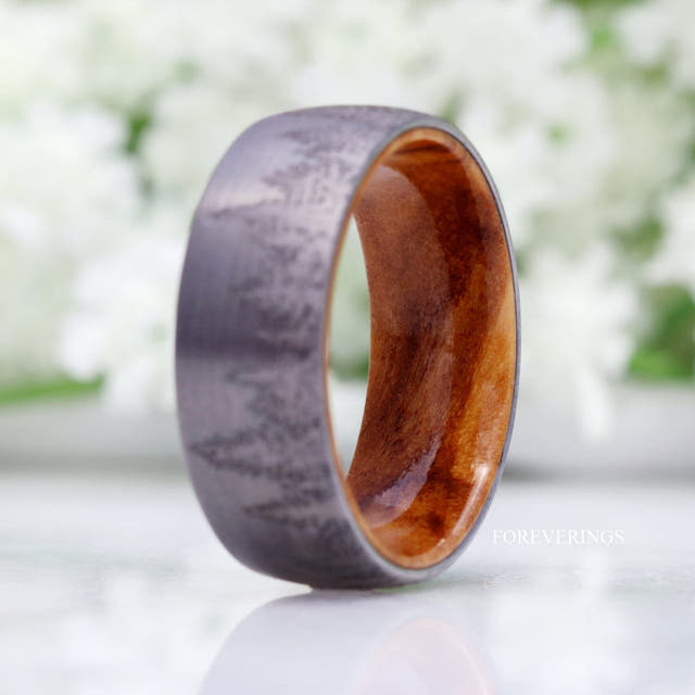 Silver tungsten tree-line band standing at an angle to show the olive wood interior, wider view