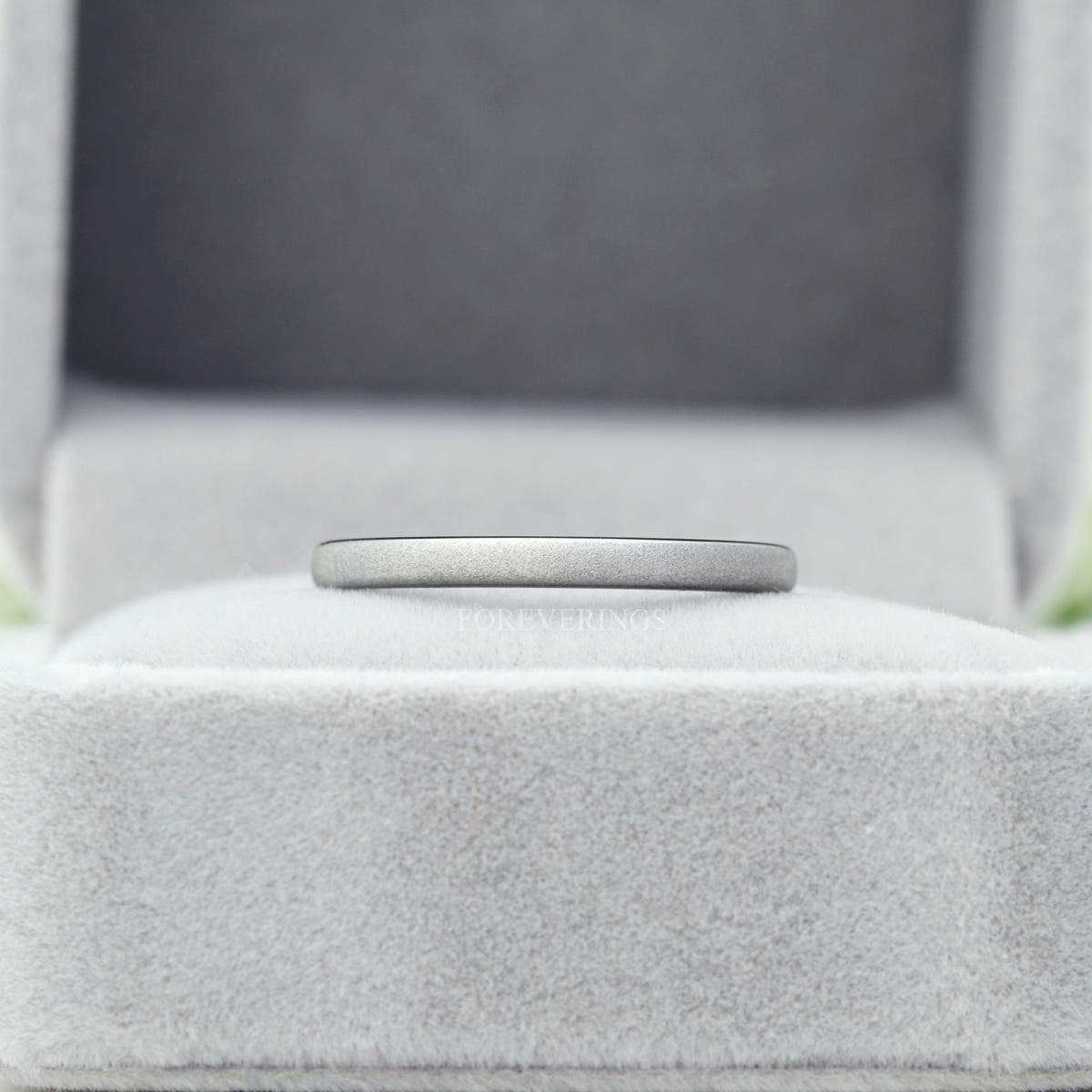 Thin sandblasted silver tungsten band in a gray ring box