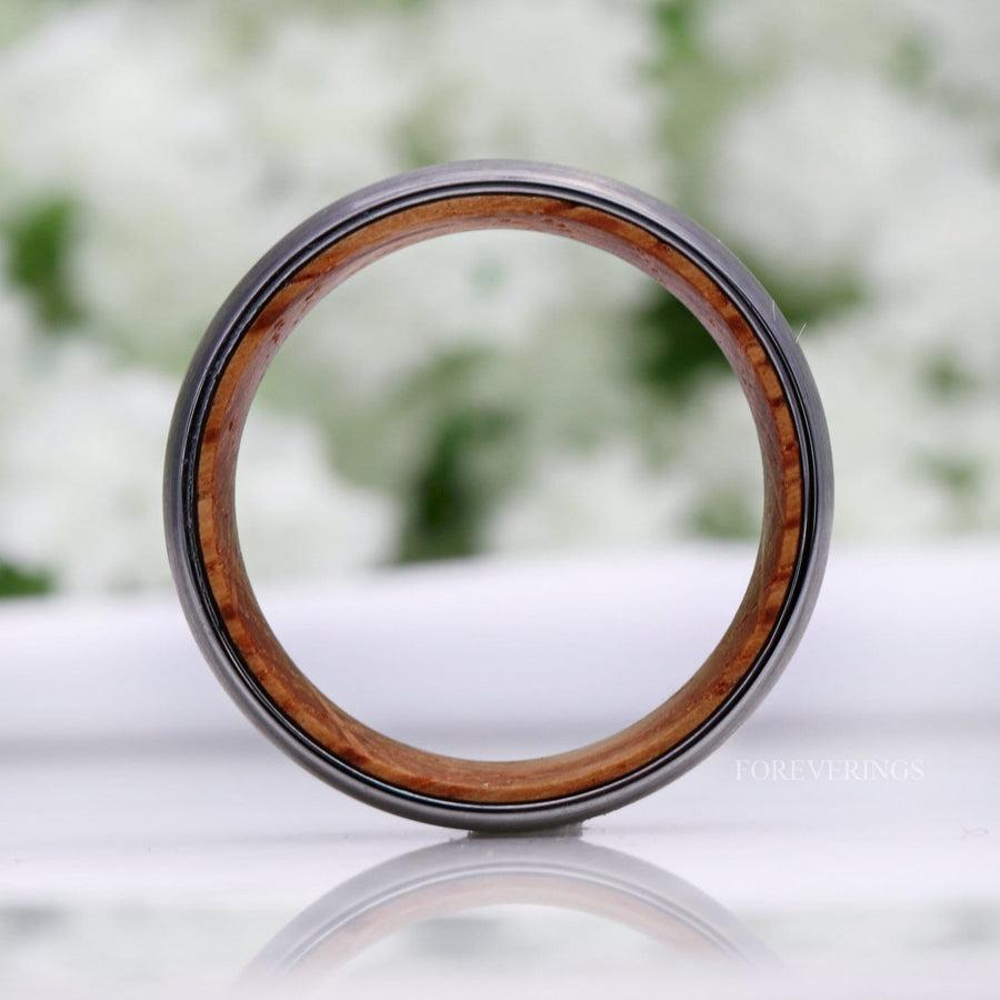 Silver tungsten whiskey barrel band seen straight on through the circle, wood lining all around