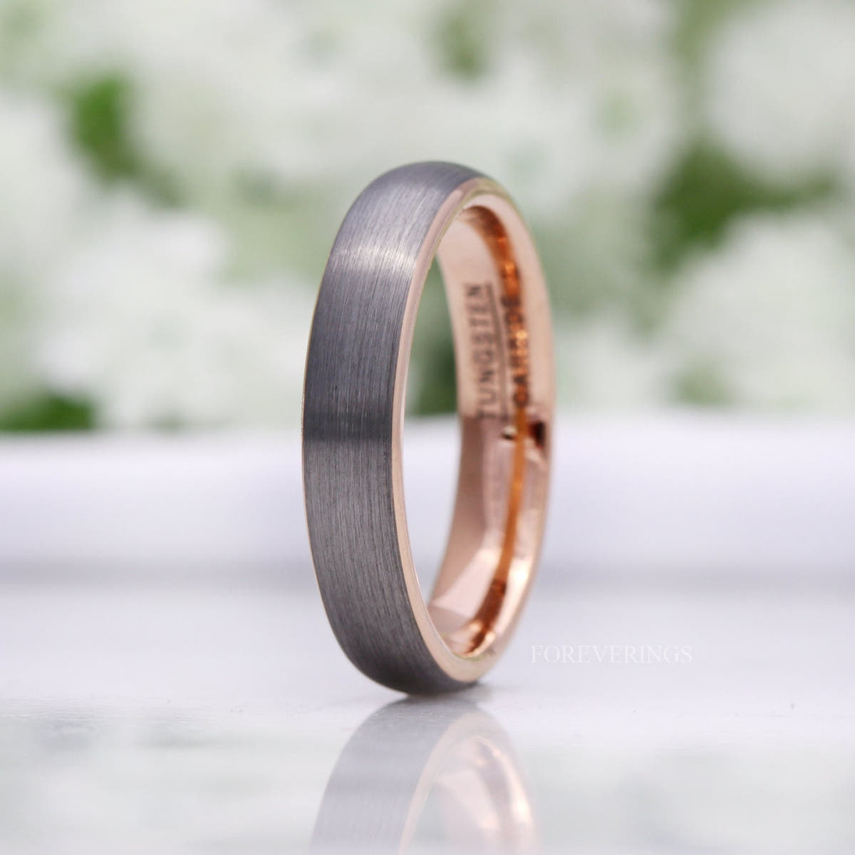 Women's 4mm matte silver tungsten band with a rose gold interior, standing at an angle