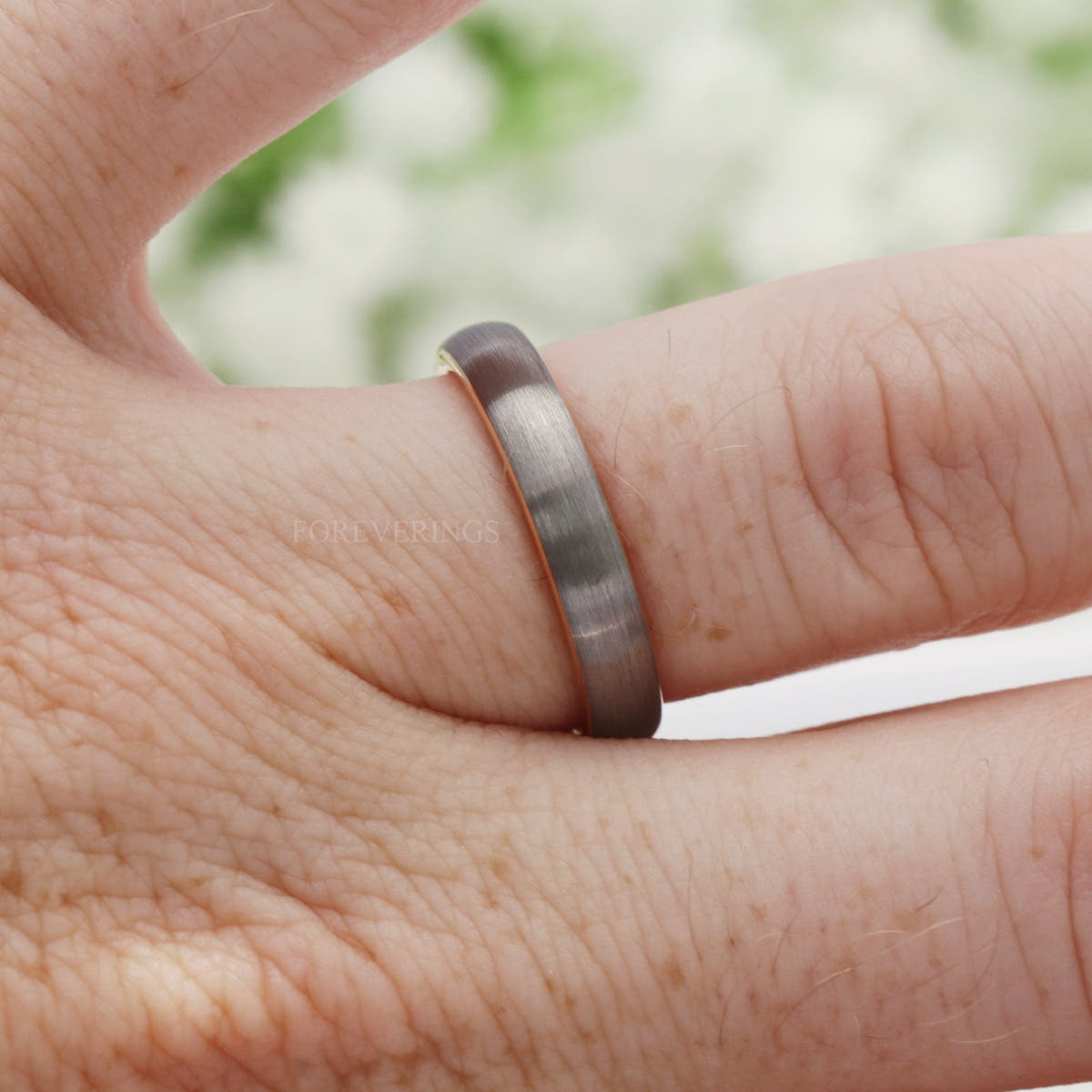 Women's 4mm silver and rose gold tungsten band worn on a finger
