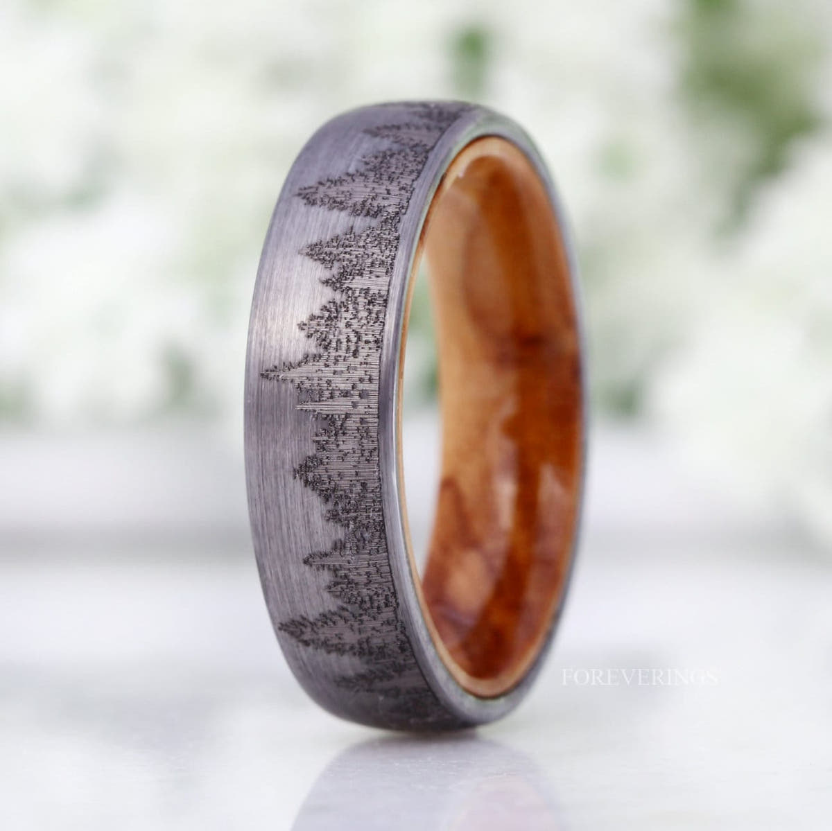 Men's 6mm silver tungsten band with an engraved forest tree-line and olive wood lining