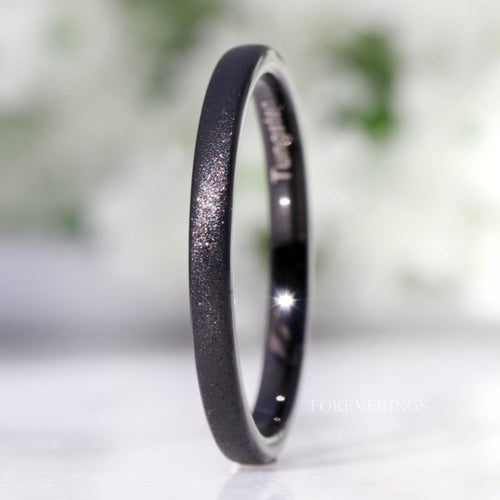 Minimalist 2mm black sandblasted tungsten ring standing on edge, close crop of the sparkling finish