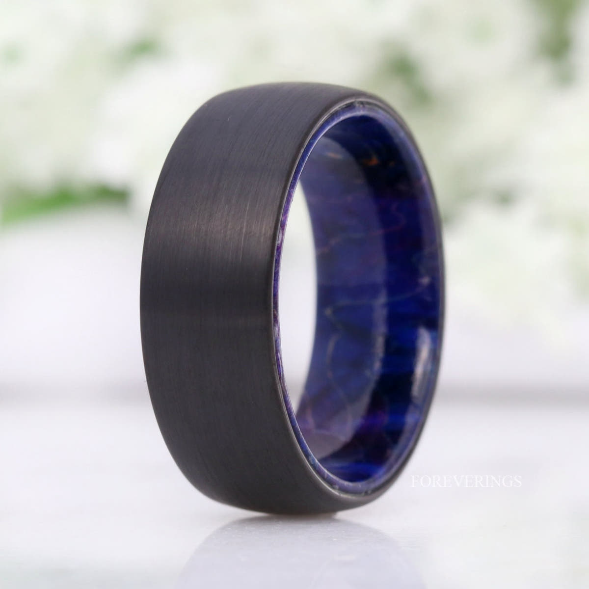 8mm brushed black tungsten band with deep blue elder wood lining, standing at an angle