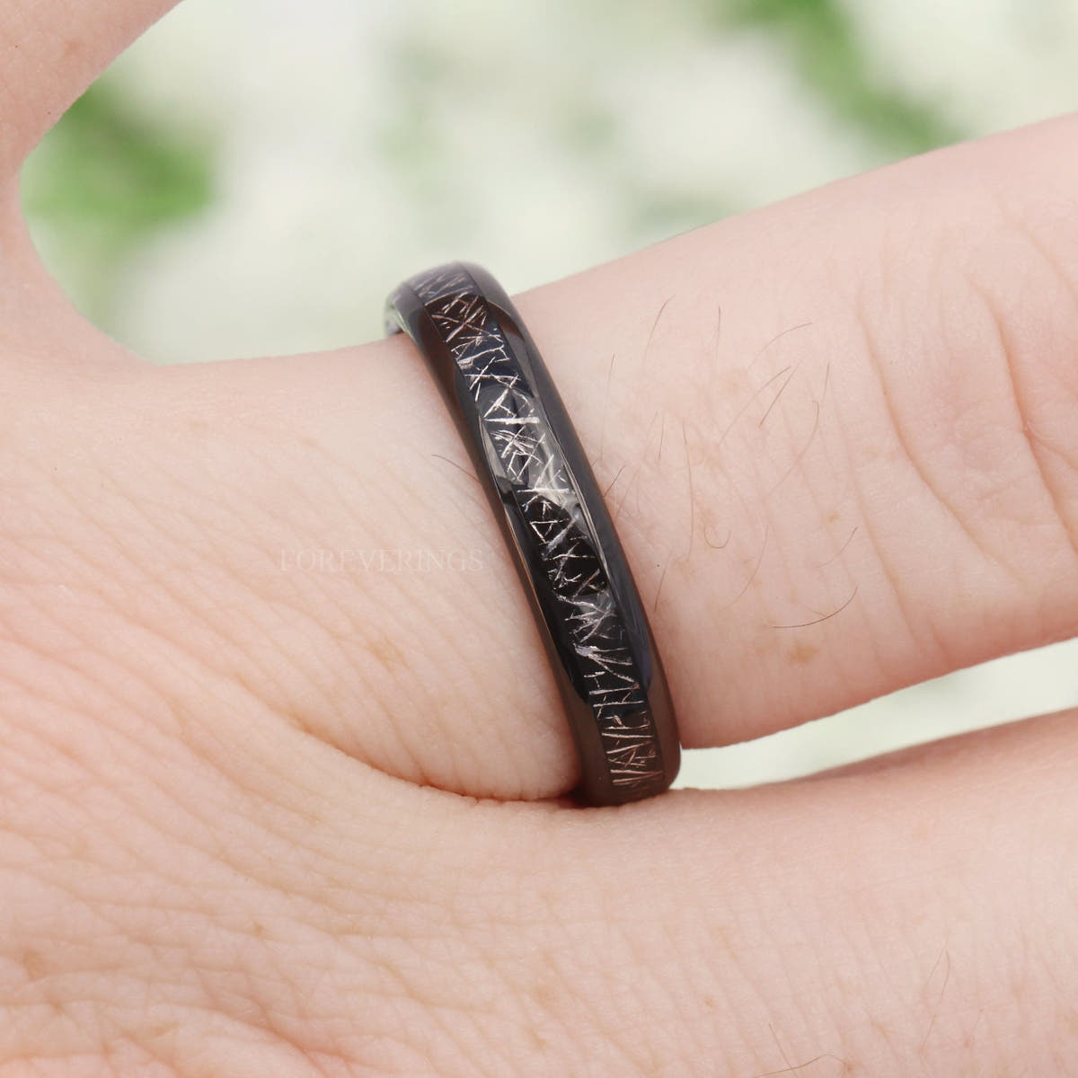 4mm black tungsten band with meteorite-look inlay worn on a finger