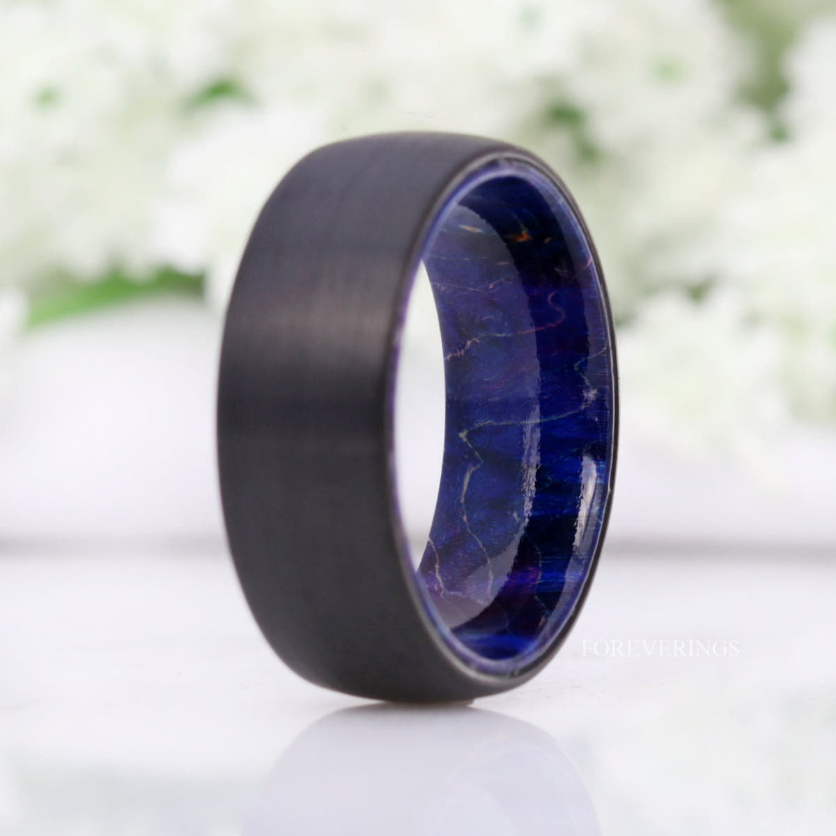 8mm black tungsten band with swirled blue elder wood lining, standing upright