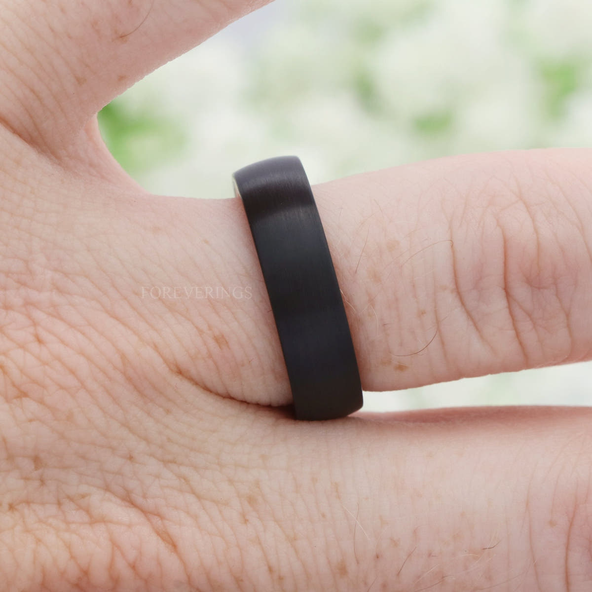 Brushed black tungsten wood-lined band worn on a finger, side view