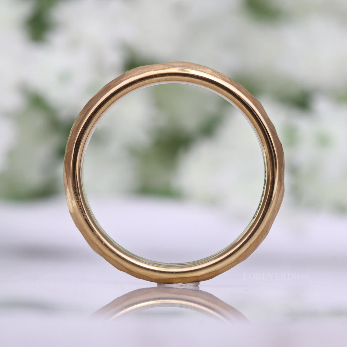 Hammered gold tungsten band seen head-on as a circle, hammered texture showing around the rim