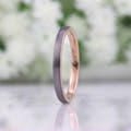 Her 2mm silver and rose gold tungsten band standing on edge, turned slightly to the side