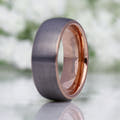 His 8mm brushed silver tungsten band standing upright, lit to show the rose gold inside