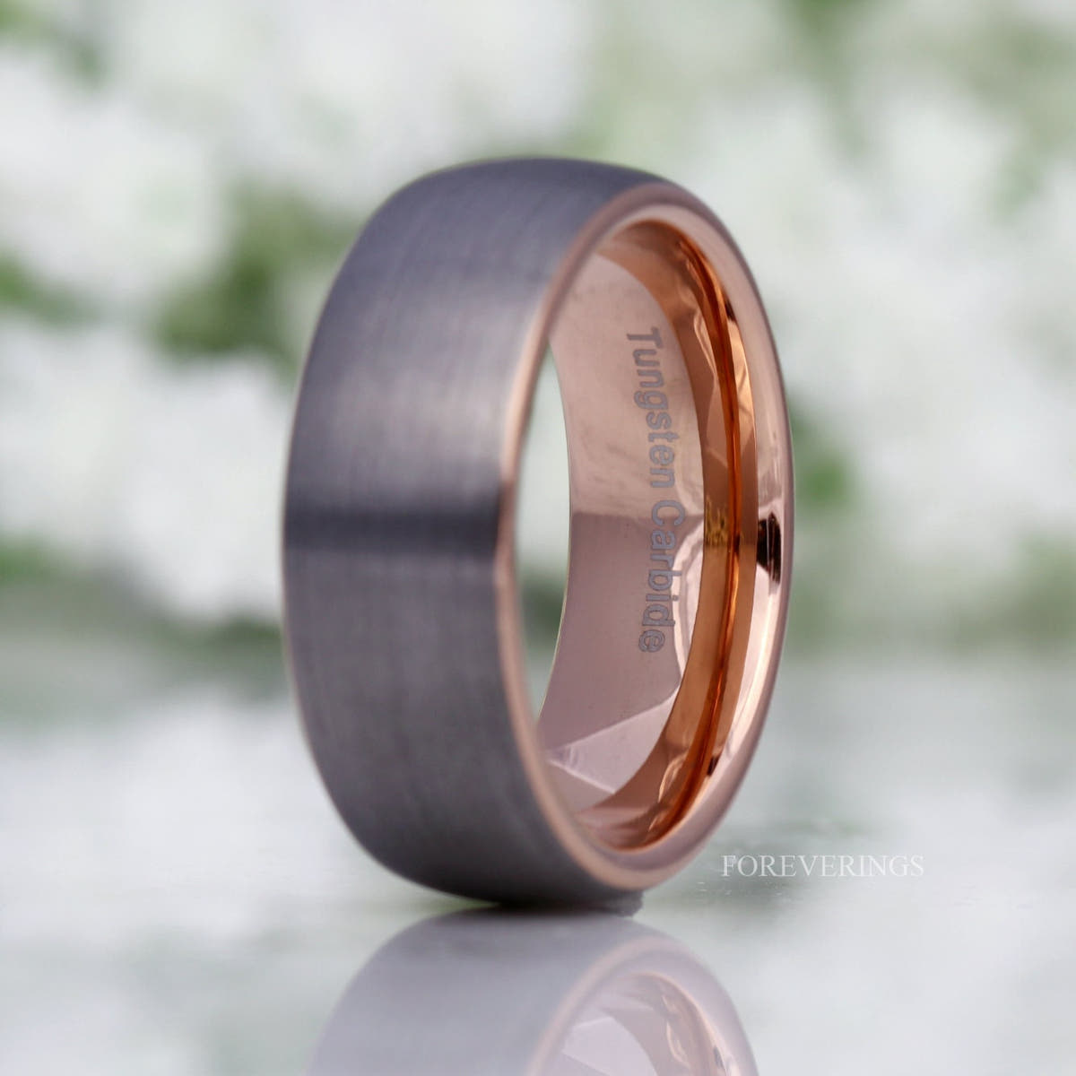 His 8mm brushed silver tungsten band standing upright, lit to show the rose gold inside