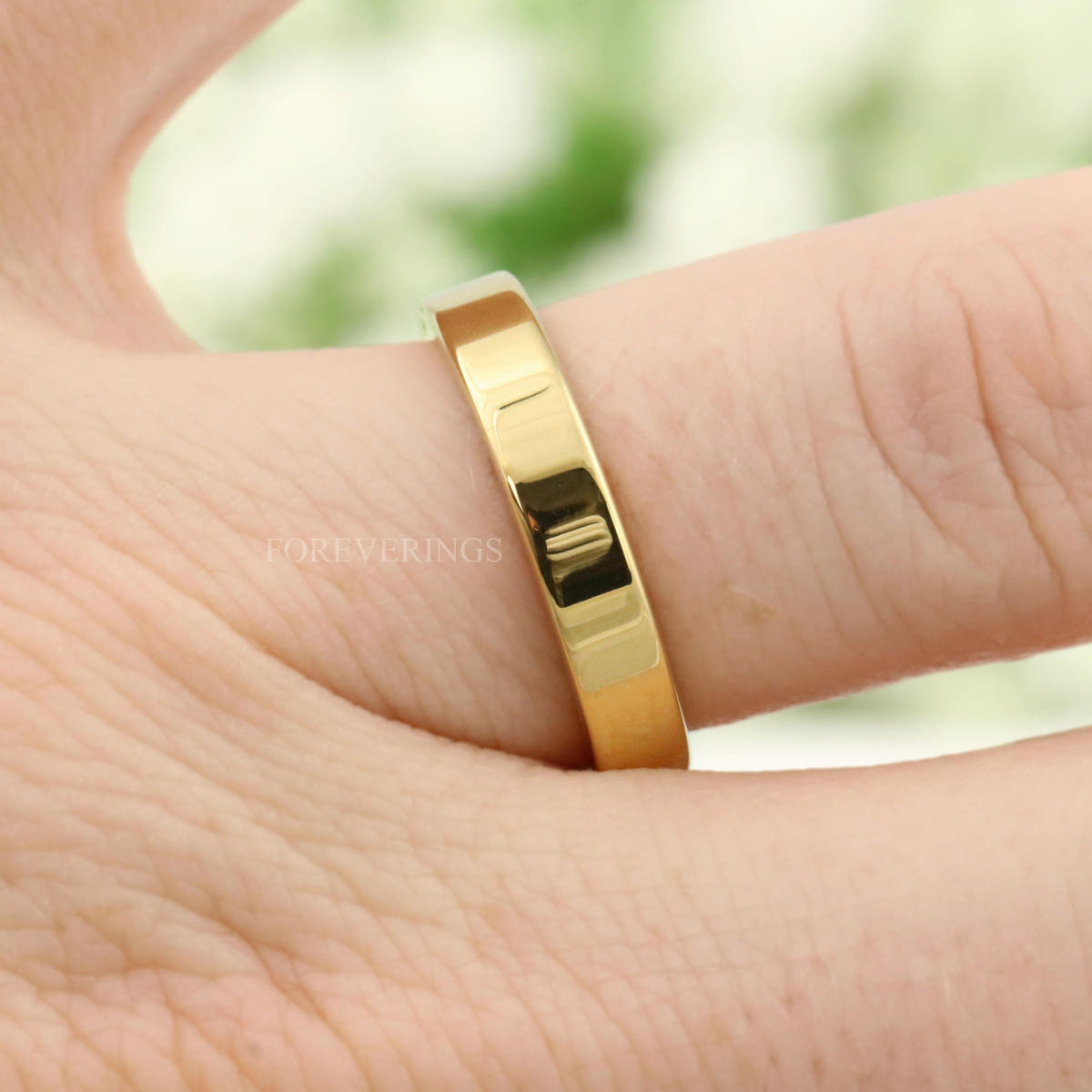 4mm flat gold tungsten wedding band worn on a finger, seen from above