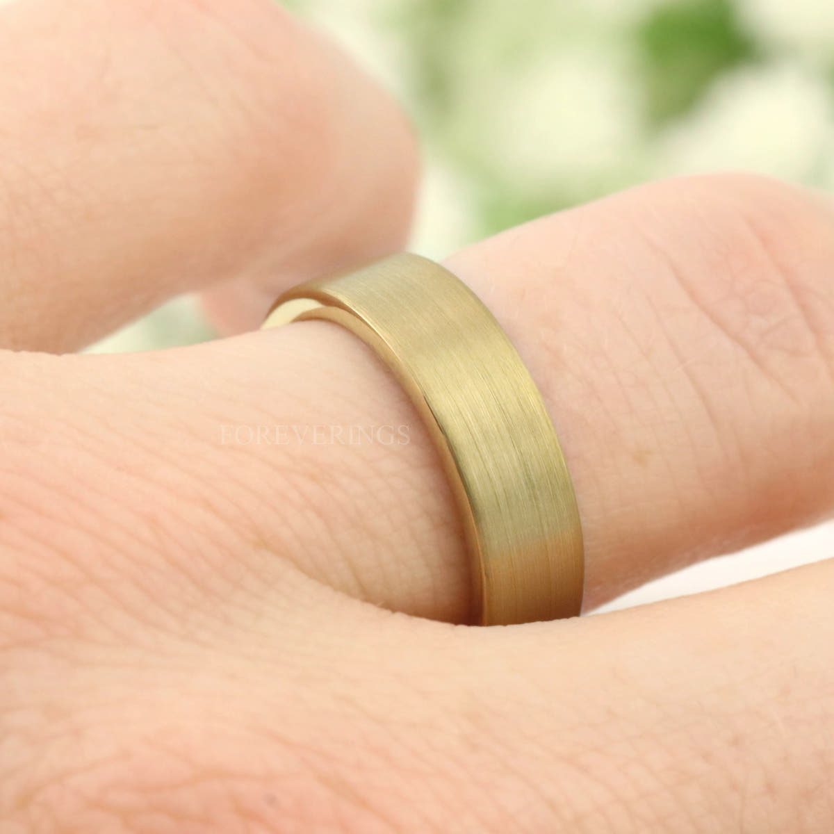 Gold tungsten band worn on a finger, low-angle close-up