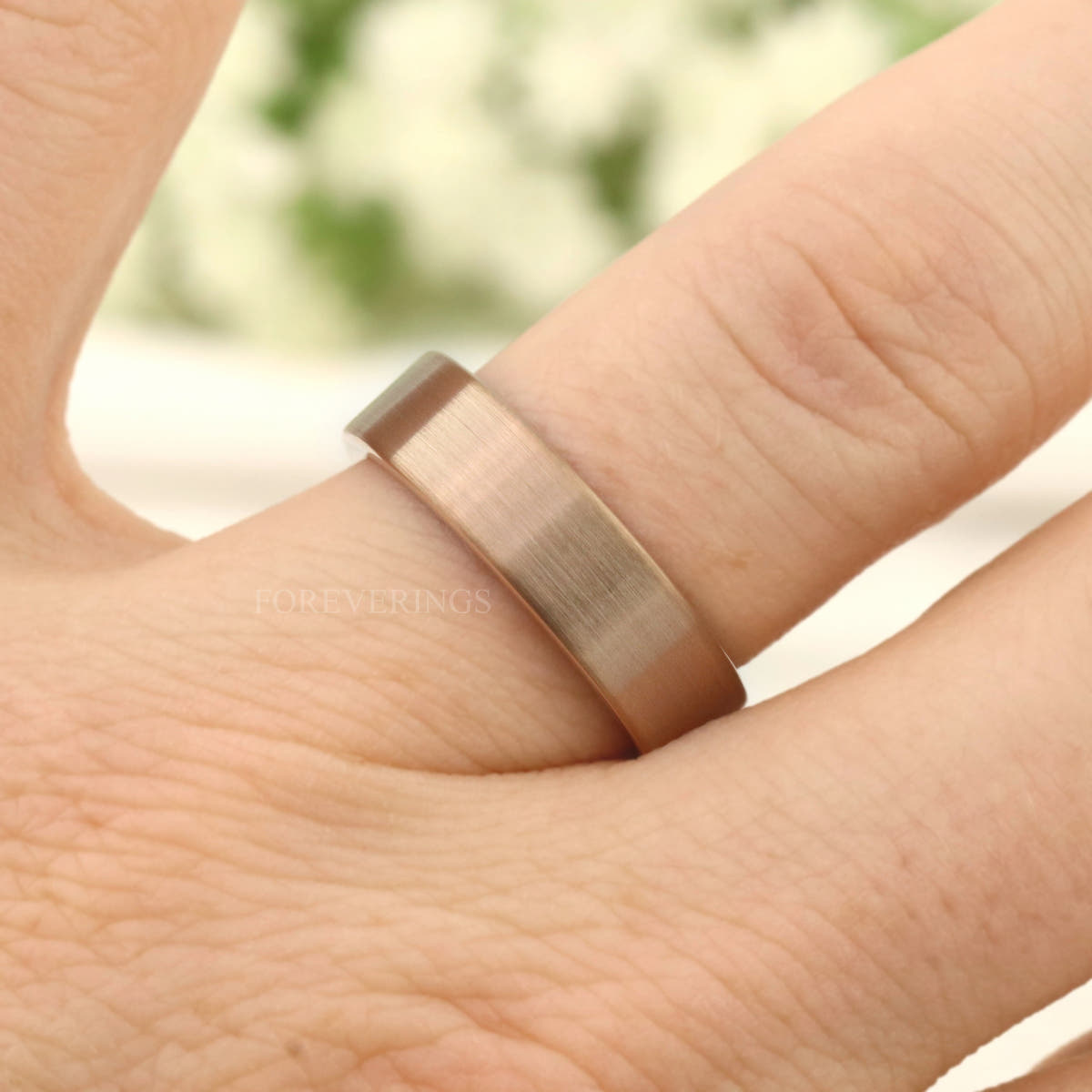 Men's 6mm matte rose gold tungsten band worn on a finger