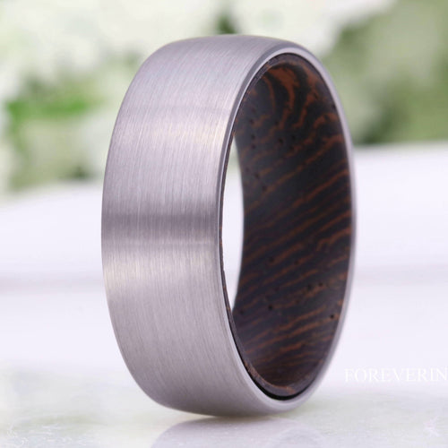 Men's 8mm brushed silver tungsten band with dark wood lining, standing in a close crop