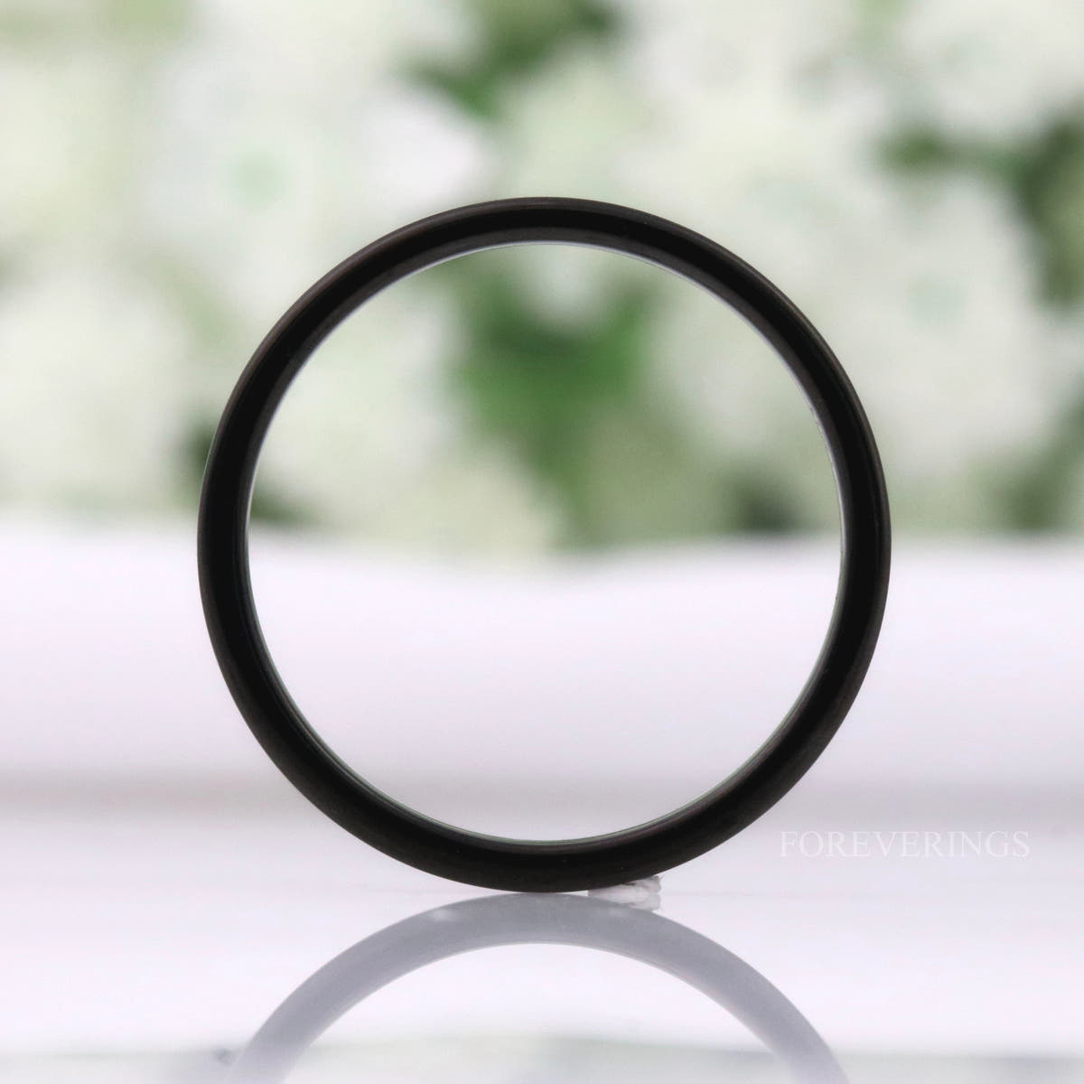 Matte black tungsten band standing on edge, seen as a full circle