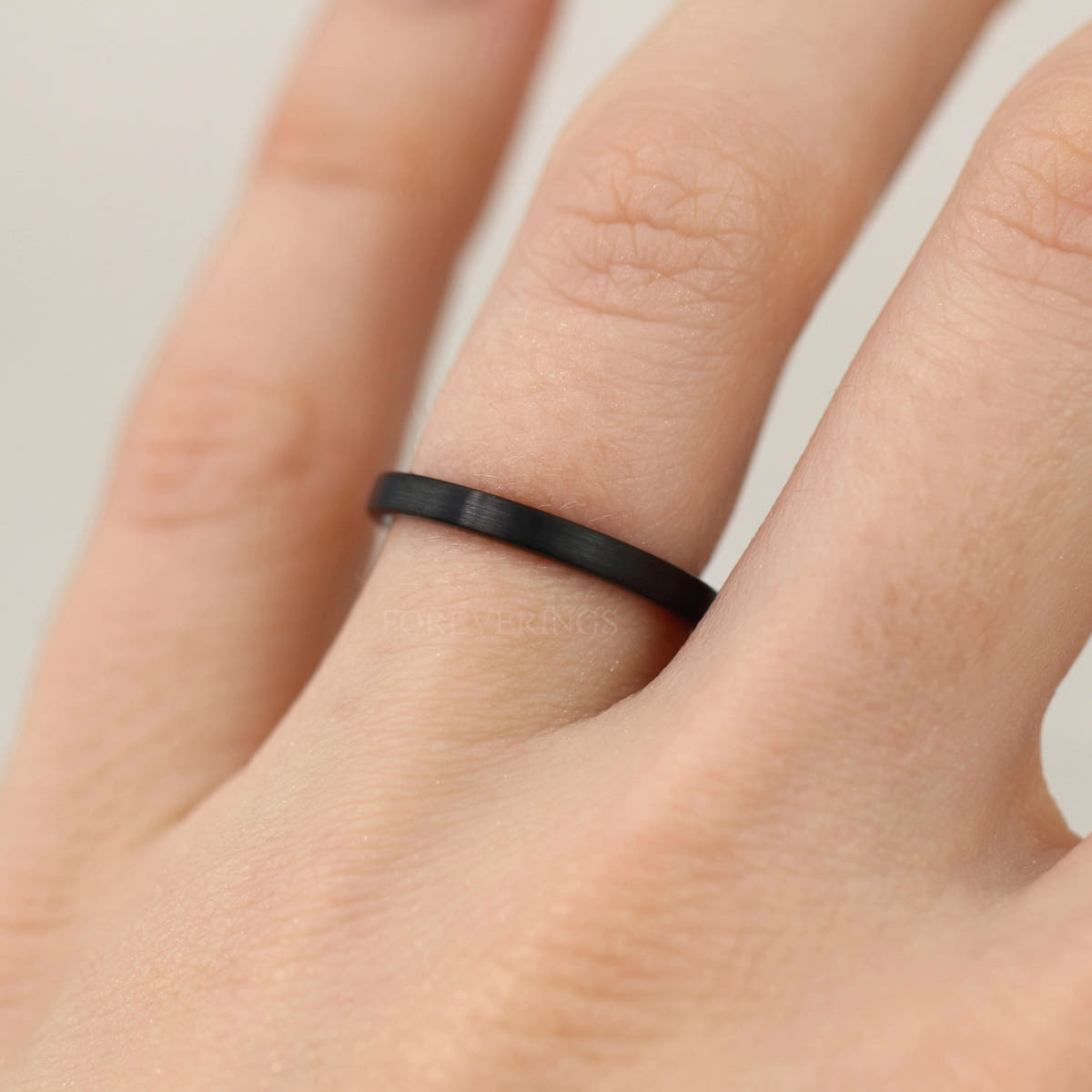Women's 2mm matte black tungsten band worn on a hand