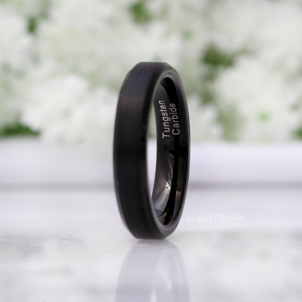 Matte black tungsten ring standing upright, close crop of the brushed finish