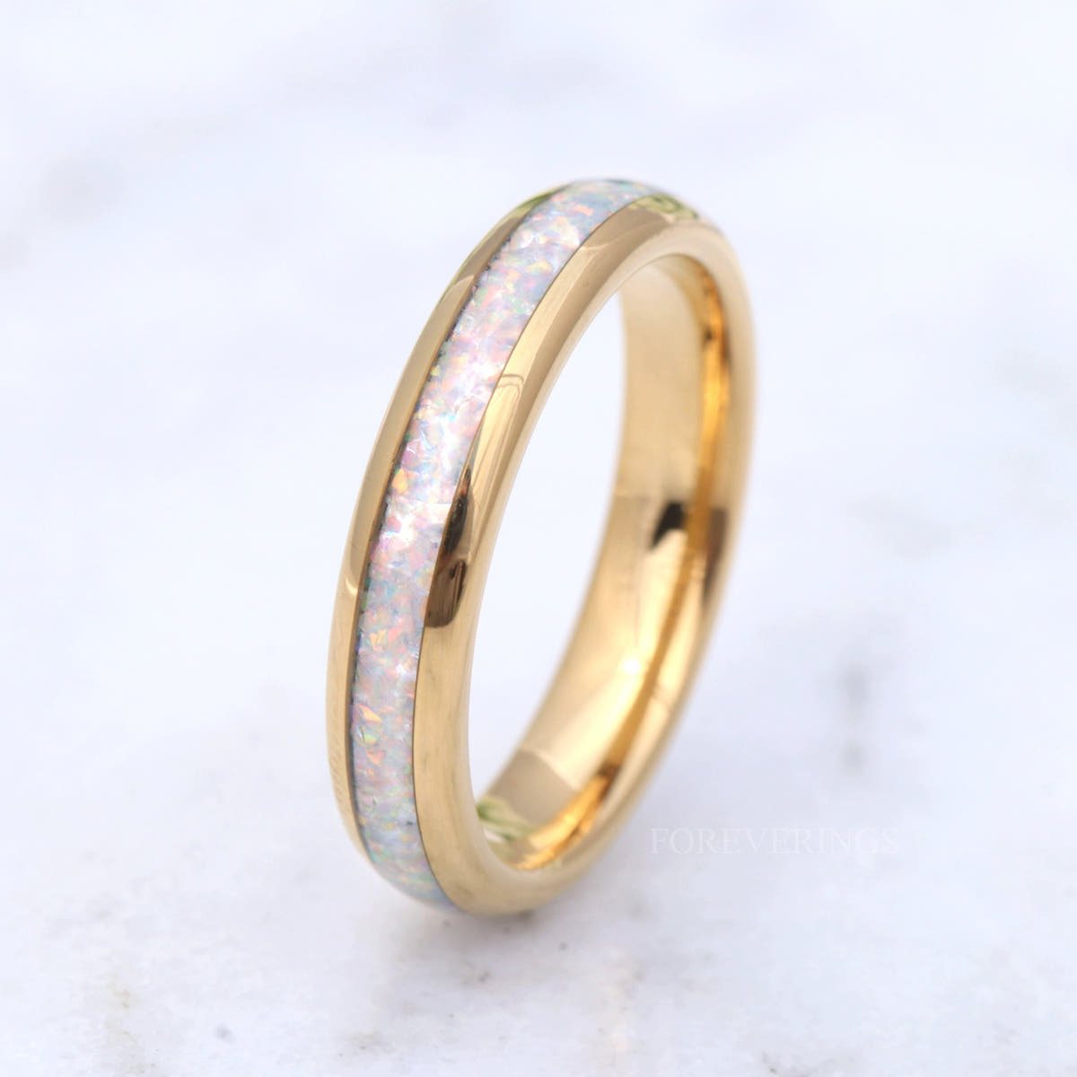 Gold tungsten band with white fire opal inlay tilted on its side, seen from above